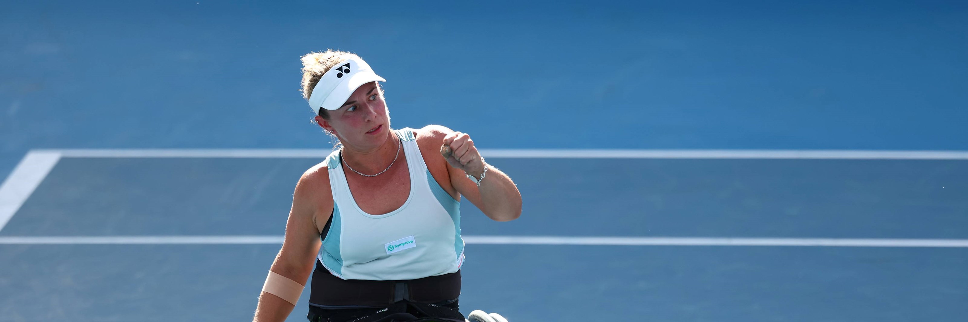 Wheelchair tennis star Lucy Shuker clenching her fist on court while holding her tennis racket