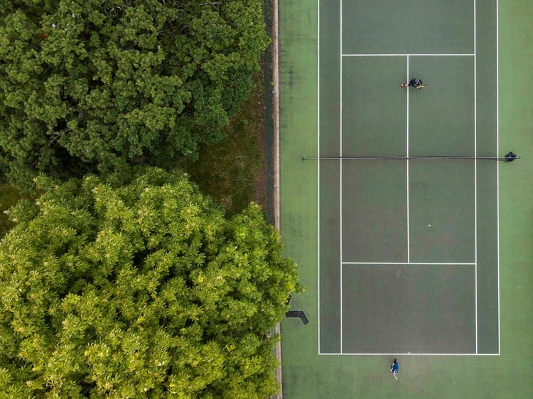 Tennis match taking place on a park tennis court